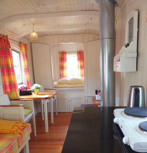 Acogedor interior de la tiny house Pipo Wagon con cortinas coloridas en Buytenplaets Suydersee, Países Bajos.