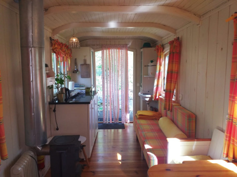 Interior de la tiny house Pipo Wagon con cortinas coloridas en Buytenplaets Suydersee, Países Bajos.