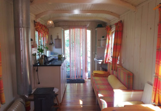 Interior de la tiny house Pipo Wagon con cortinas coloridas en Buytenplaets Suydersee, Países Bajos.