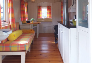 Intérieur de la tiny house Pipo Wagon à Buytenplaets Suydersee aux Pays-Bas, rideaux colorés aux fenêtres.