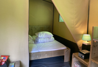 Innenaufnahme eines Safari-Zelts mit Doppelbett, Nachttisch, Lampe und Snacks bei Buytenplaets Suydersee.