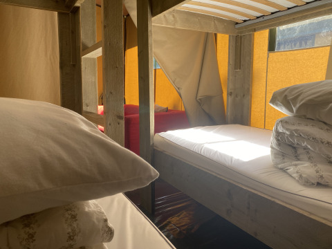 Inde i et safari-telt med køjesenge, puder og morgendagslys på Buytenplaets Suydersee i Holland.
