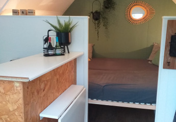Innenraum einer Hiker's Cabin bei Buytenplaets Suydersee, Niederlande, mit Bett, Pflanzen und Spiegel.