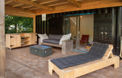 Covered terrace with wooden furniture at Sea Container tiny house, Buytenplaets Suydersee, in the Netherlands.