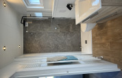 Moderno bagno nel chalet Sea bass all'Holiday Park de Zeeuwse Parel, Paesi Bassi, con doccia in vetro e pavimento in legno.