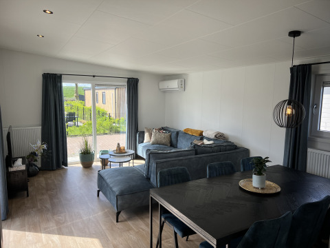 Lyst opholdsområde i chalet Sea bass ved Holiday Park de Zeeuwse Parel med moderne møbler og udsigt.