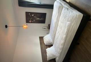 Soveværelse med dobbeltseng, moderne indretning og vægkunst i Sea bass-chalet, Holiday Park de Zeeuwse Parel.