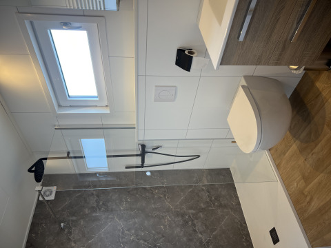 Moderne badeværelse med brusekabine, væghængt toilet og vindue i chalet Sea bass i Holiday Park de Zeeuwse Parel.