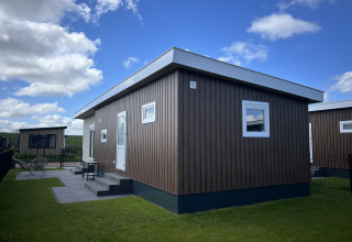 Modern chalet Sea Bass at Holiday Park de Zeeuwse Parel, Netherlands, featuring a wood facade and lawn.