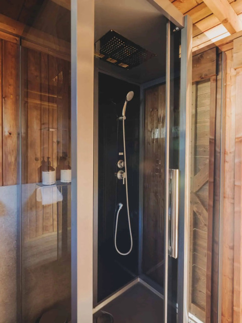 Moderne douchecabine in een safaritent op Wecamp L'Escala Punta Mila, Spanje, met houten afwerking.