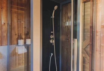 Moderne douchecabine in een safaritent op Wecamp L'Escala Punta Mila, Spanje, met houten afwerking.