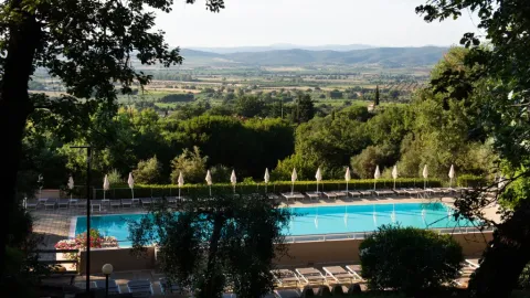 Vue sur la piscine et les transats du Vallicella Glamping Resort avec la campagne toscane à l'arrière-plan.