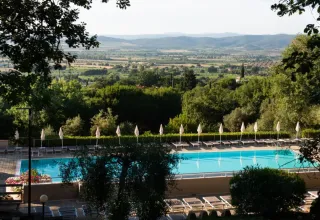 Uitzicht op het zwembad en ligstoelen aan Vallicella Glamping Resort met Toscaans landschap op de achtergrond.