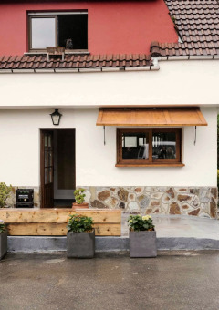 Entrance of a holiday park house at Wecamp Cudillero, Asturias, with potted plants and a stone facade.
