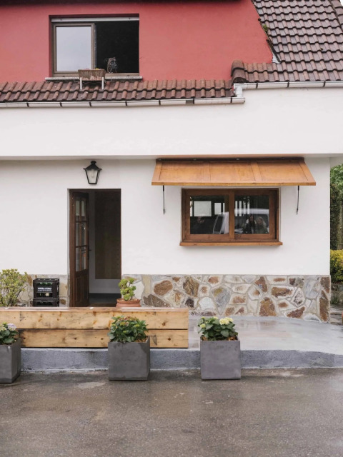 Eingang eines Ferienhauses im Wecamp Cudillero, Asturias, mit Blumentöpfen und markantem roten Dach.