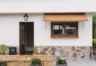 Eingang eines Ferienhauses im Wecamp Cudillero, Asturias, mit Blumentöpfen und markantem roten Dach.