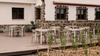 Outdoor terrace at Wecamp Cudillero holiday park in Asturias, Spain, featuring tables, chairs, and stone house.