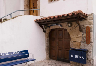Eingang eines Gebäudes in Cudillero, Asturien, Spanien, mit Sitzbank und Schildern Ribera und Pescaderia.