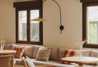 Gemütlicher Loungebereich im Wecamp Cudillero, Asturias, Spanien, mit Sitzbank, Holz- und Korbmöbeln.