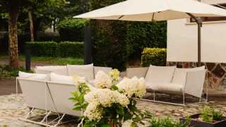 Modern outdoor lounge with white sofas, umbrellas, and flowers at Wecamp Cudillero holiday park, Spain.