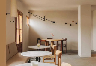 Heller, minimalistischer Cafébereich mit runden Tischen und Holzmöbeln in Wecamp Cudillero, Asturien.