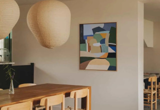 Esszimmer im Wecamp Cudillero Ferienpark in Asturien, Spanien, mit Holzstühlen und moderner Kunst.