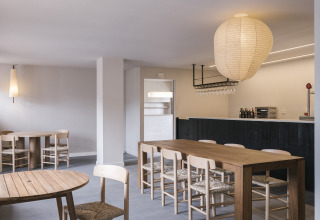 Modernes Café-Innere im Wecamp Cudillero, Asturien, mit Holzmöbeln, Bar und stilvoller Beleuchtung.