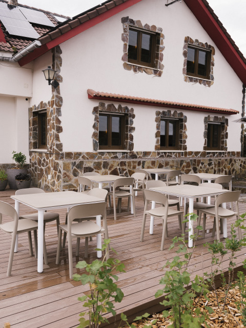 Außenterrasse mit modernen Tischen und Stühlen vor einem Steinhaus im Wecamp Cudillero, Asturias, Spanien.