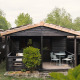 Black wooden bungalow with small patio, garden furniture, and greenery at Bungalow Basic Family Plus.