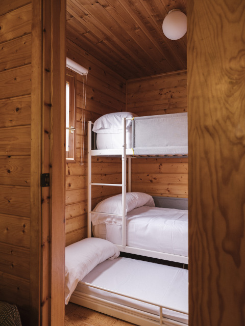 Habitación con literas y paneles de madera en Bungalow Basic Family Plus de Wecamp Cudillero, España.