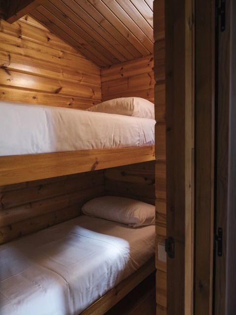 Litera con dos camas individuales en una tiny house de madera en Wecamp Cudillero, España.
