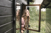 Woman looking out an open window of the black tiny house Bungalow «Basic Couple» at Wecamp Cudillero, Spain.