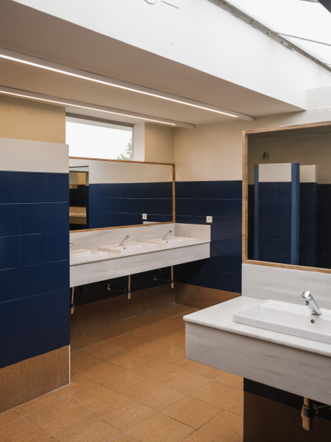Salle de bains moderne avec carrelage bleu, lavabos blancs et grands miroirs au Cottage Family Tent, Wecamp Cudillero, Espagne.
