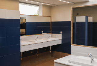 Salle de bains moderne avec carrelage bleu, lavabos blancs et grands miroirs au Cottage Family Tent, Wecamp Cudillero, Espagne.