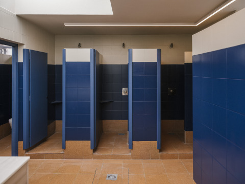 Salle de bains partagée avec carrelage bleu et blanc et douches individuelles à Wecamp Cudillero, Espagne.