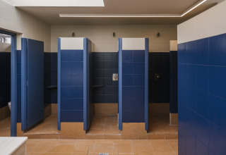 Salle de bains partagée avec carrelage bleu et blanc et douches individuelles à Wecamp Cudillero, Espagne.