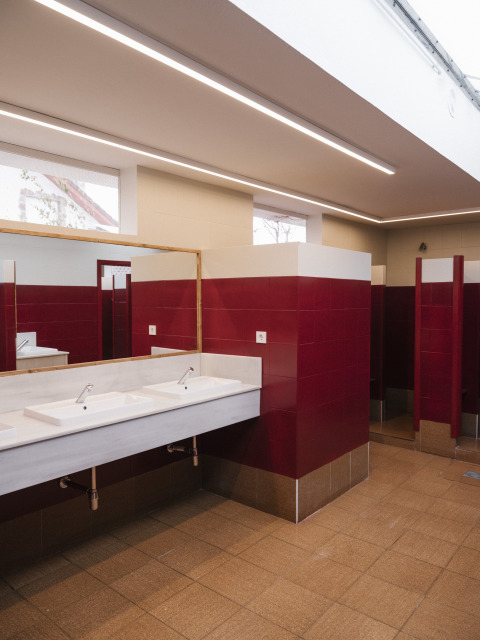 Salle de bain moderne avec carrelage rouge, double vasque et cabines ouvertes au Cottage Family Tent, Wecamp Cudillero, Espagne.