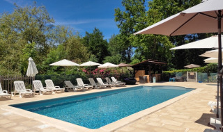Piscine extérieure du camping Pagel en Occitanie, France, avec transats et parasols sous le soleil.