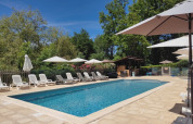 Outdoor pool at Campsite Pagel in Occitanie, France, with deck chairs and umbrellas under blue sky.