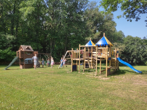 Bambini giocano su un parco giochi di legno con scivoli a Campsite Pagel, parco vacanze in Occitania, Francia.