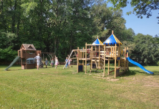 Bambini giocano su un parco giochi di legno con scivoli a Campsite Pagel, parco vacanze in Occitania, Francia.