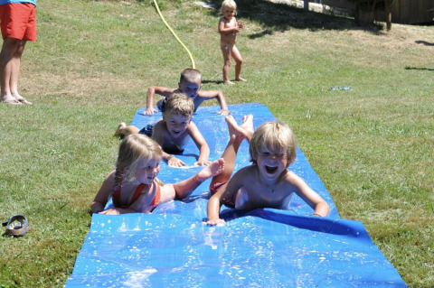 Kids play and laugh on a waterslide at Campsite Pagel, a family holiday park in Occitanie, France.