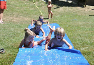 Bambini che si divertono su uno scivolo d’acqua al campeggio Pagel, parco vacanze in Occitania, Francia.