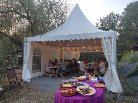 Outdoor dinner under a marquee at Campsite Pagel in Occitanie, France, with food on a table and guests dining.