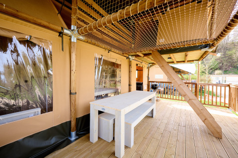Veranda esterna con tavolo in legno e soffitto a rete nella tenda safari Ranger al campeggio Spina Family Collection in Italia.