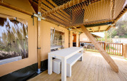 Buitenveranda met houten tafel en netplafond aan Ranger safaritent op Spina Family Collection camping in Italië.