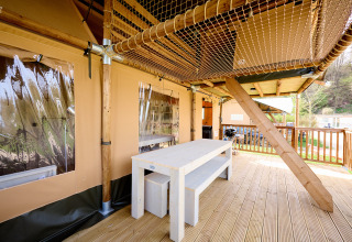 Terrasse mit Holztisch und Netzdecke an einem Ranger Safari-Zelt auf dem Spina Family Collection Campingplatz in Italien.