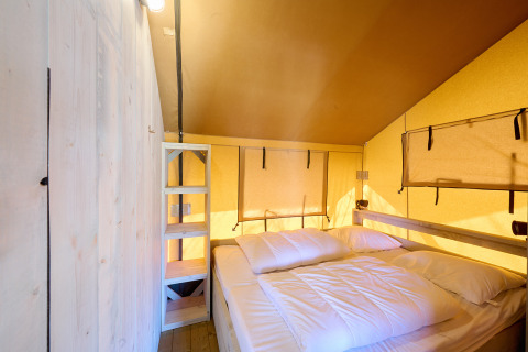 Innenansicht eines Ranger Safari-Zeltes auf dem Campingplatz Spina Family Collection in Italien mit Bett.