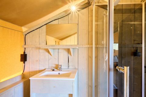 Bathroom in the Ranger safari tent at Spina Family Collection Campsite, featuring a sink, mirror, and shower.