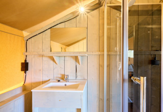 Bathroom in the Ranger safari tent at Spina Family Collection Campsite, featuring a sink, mirror, and shower.